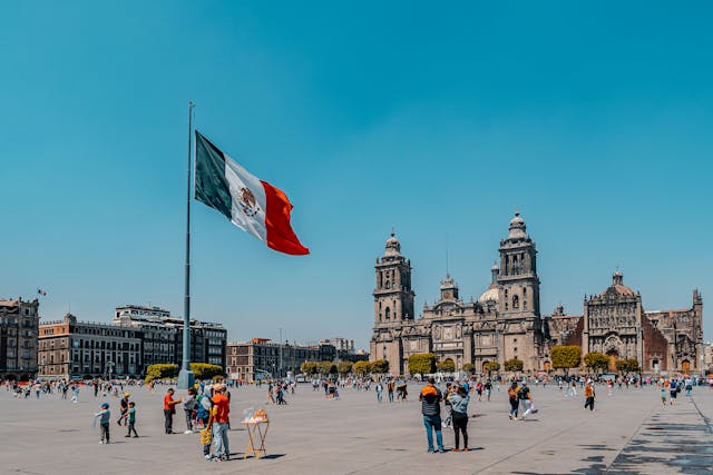 Imagen del Zócalo de Ciudad de México con turistas, la bandera mexicana y la Catedral Metropolitana, lugar turístico ideal para visitar tras mudanzas a México.